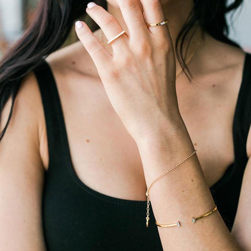 Woman wearing a black tank top and Katie Dean rings and bracelets.