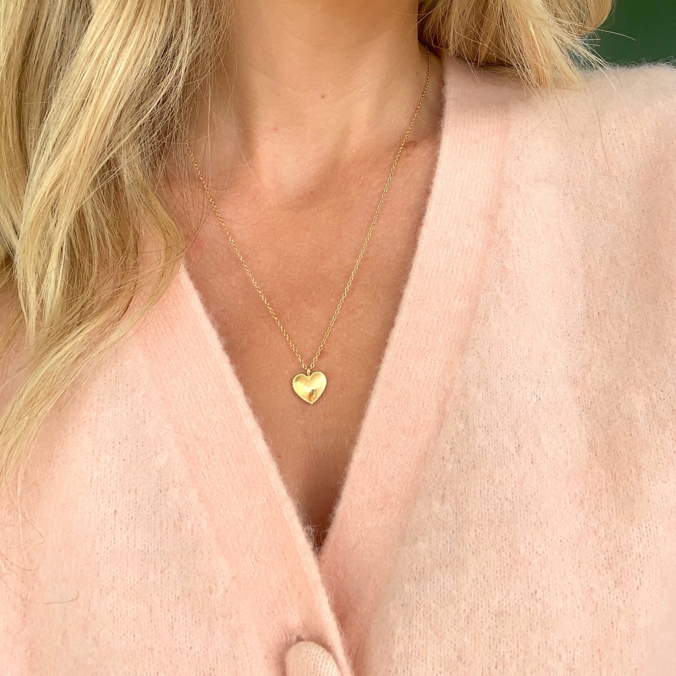 Gold Beaded Heart Necklace by Katie Dean Jewelry as seen on a model with a pink cardigan sweater.