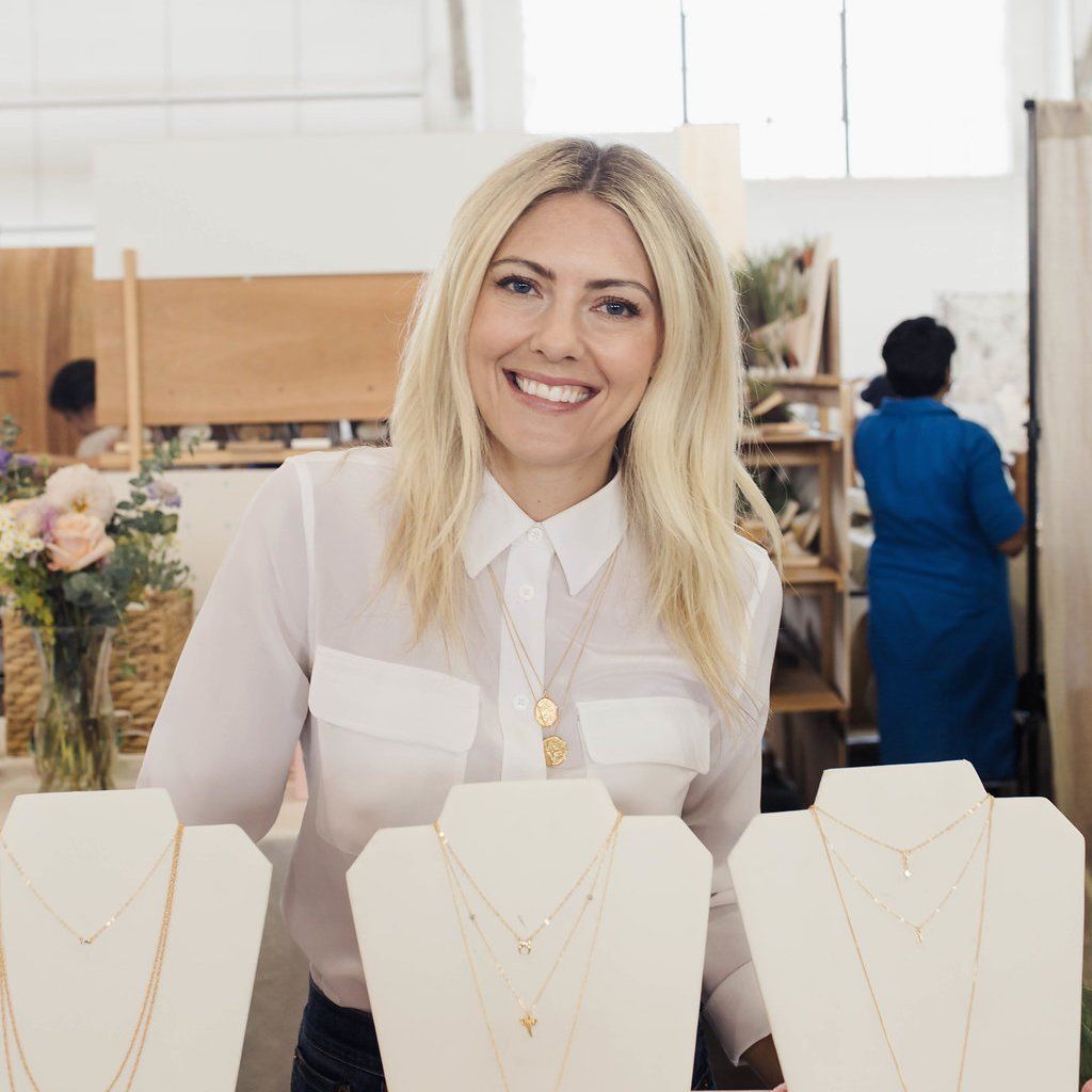 Katie Dean, founder and designer of Katie Dean Jewelry, smiling at the camera at her Renegade Craft Fair booth in San Francisco