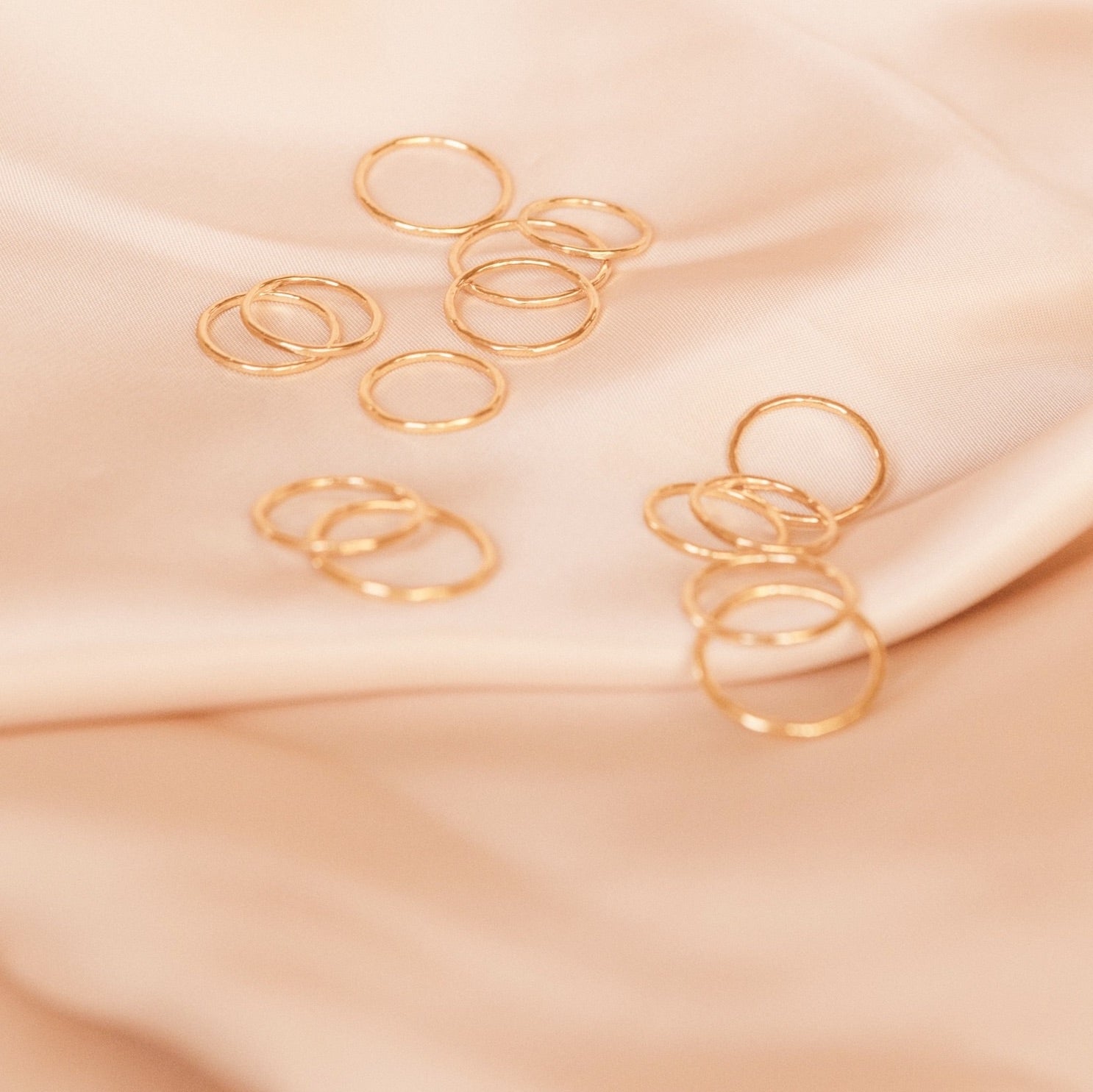 Rings on pink satin, stacking Hammered Band Rings, made in America by Katie Dean Jewelry