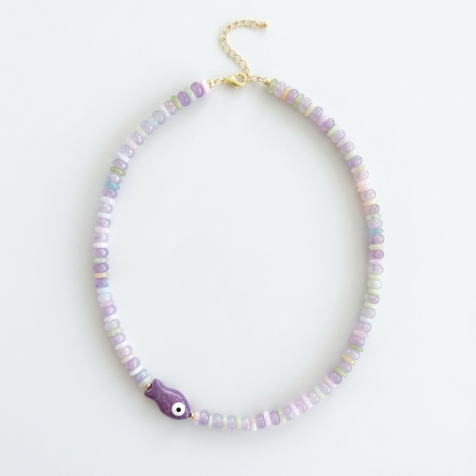 Necklace with pastel beads and a purple fish charm on a white background