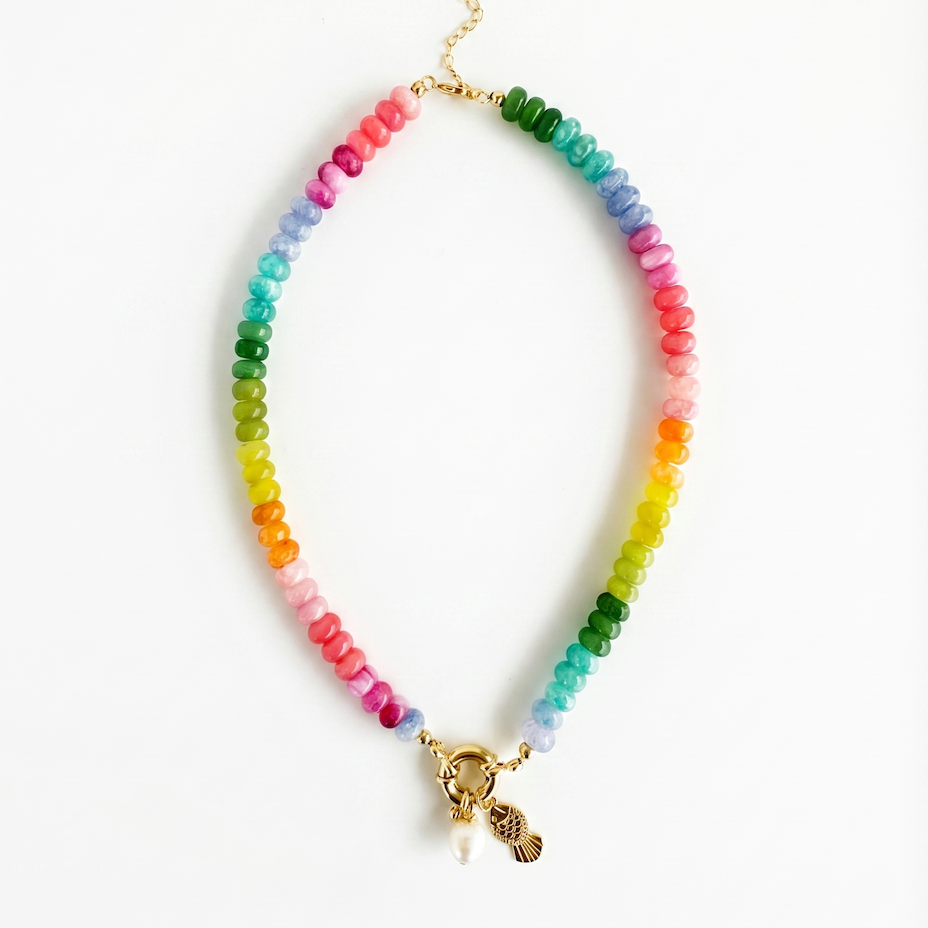 rainbow gemstone bead necklace with pearl charm and gold fish charm detail in multicolor tones on a white background.