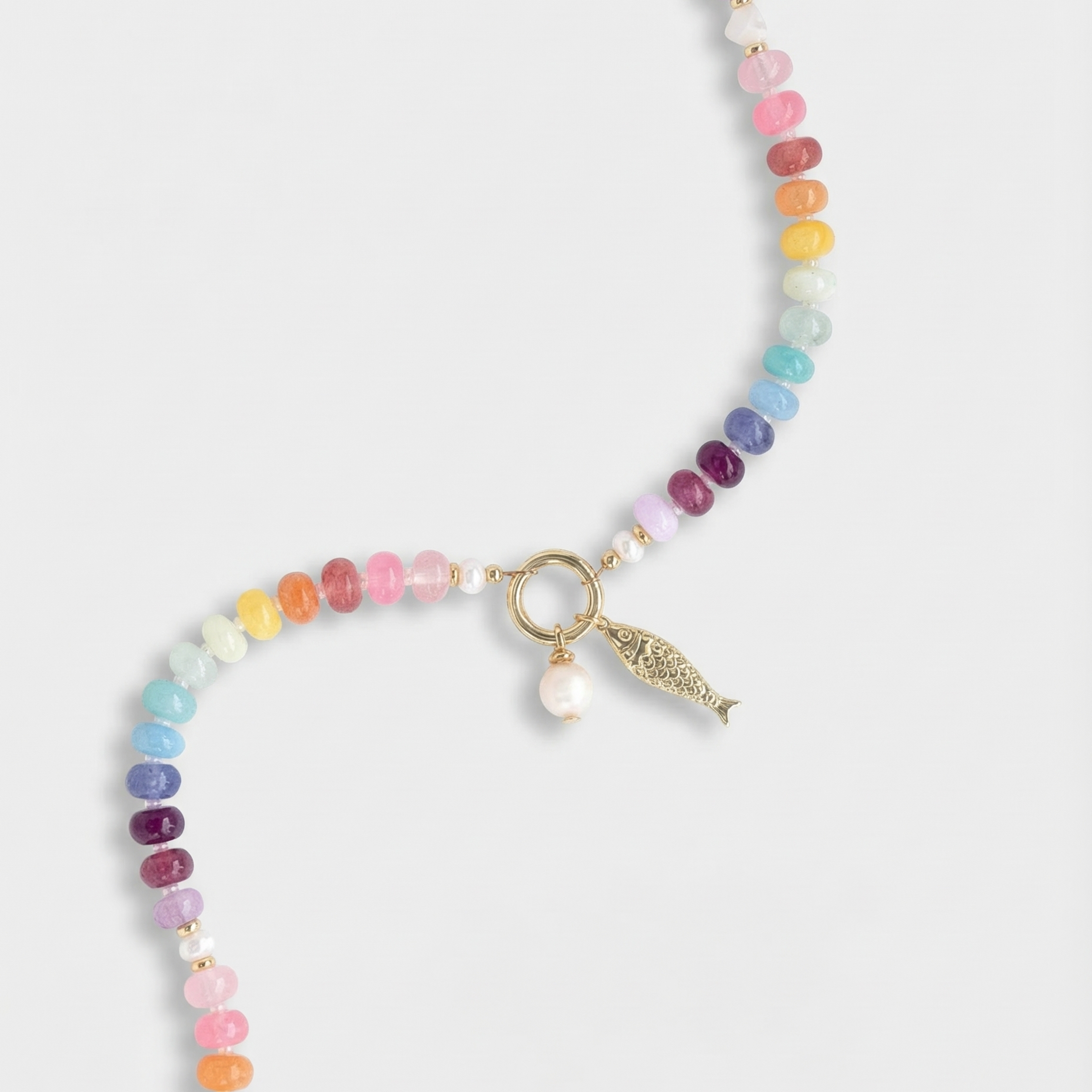 Multicolored beaded necklace with a gold fish charm and a pearl charm on a white background
