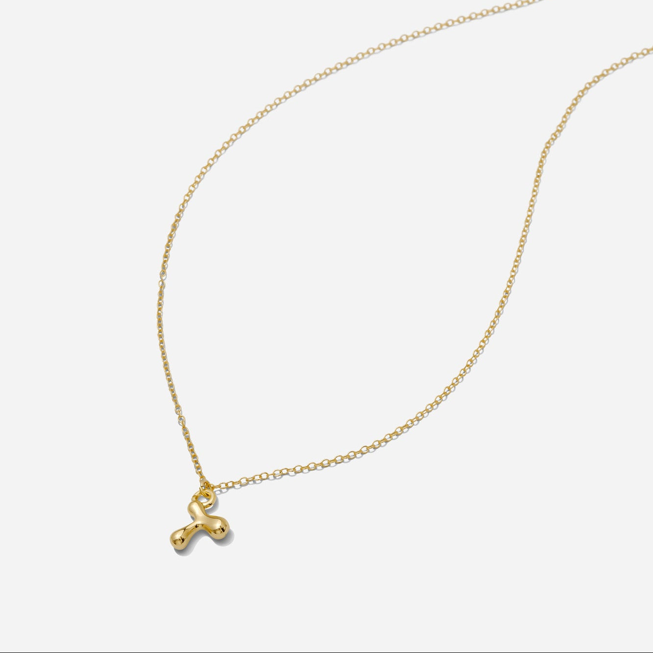 Dainty Gold puffy initial "T" pendant necklace on an 18-inch gold filled chain as seen on a white background.