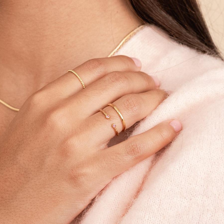 Hand on shoulder wearing the Birthstone Ring and Hammered Band Ring.