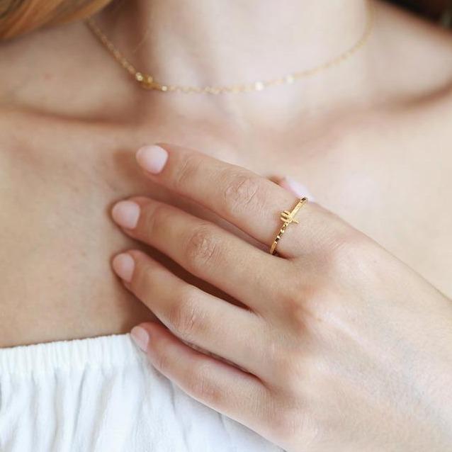 Model wearing the thin gold band ring with a small cactus charm on top of the band of the ring, in gold.