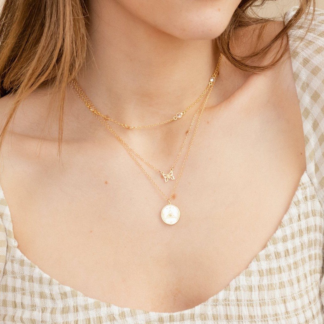 Model wearing a gold dainty necklace with round charm with an all seeing eye design, designed and made by Katie Dean Jewelry