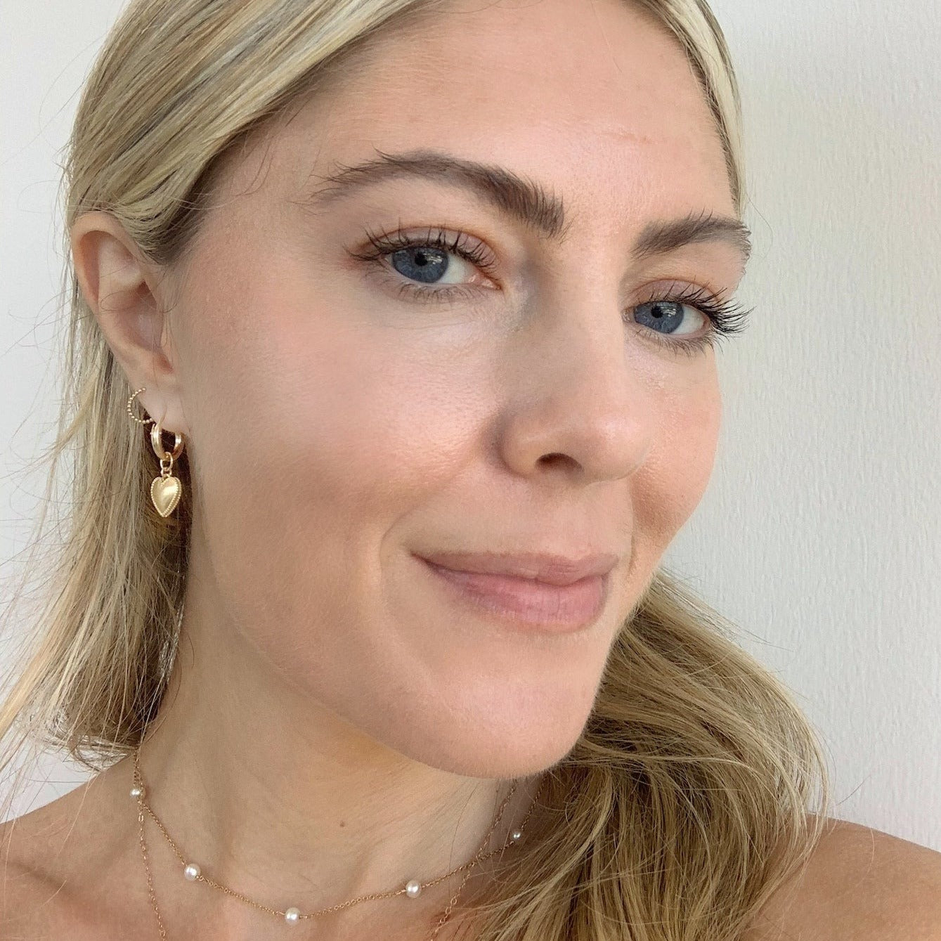 Dainty gold Heart Hoops hand crafted by Katie Dean Jewelry in America as seen on a model