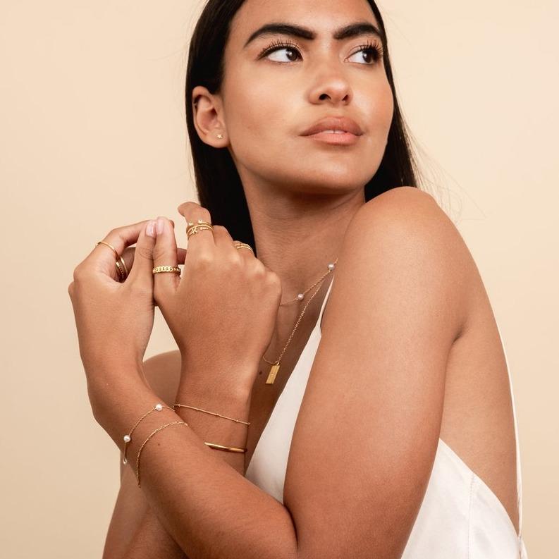 Pearl chain bracelet shown on a model crossing her arms and looking to the side, jewelry made by Katie Dean Jewelry