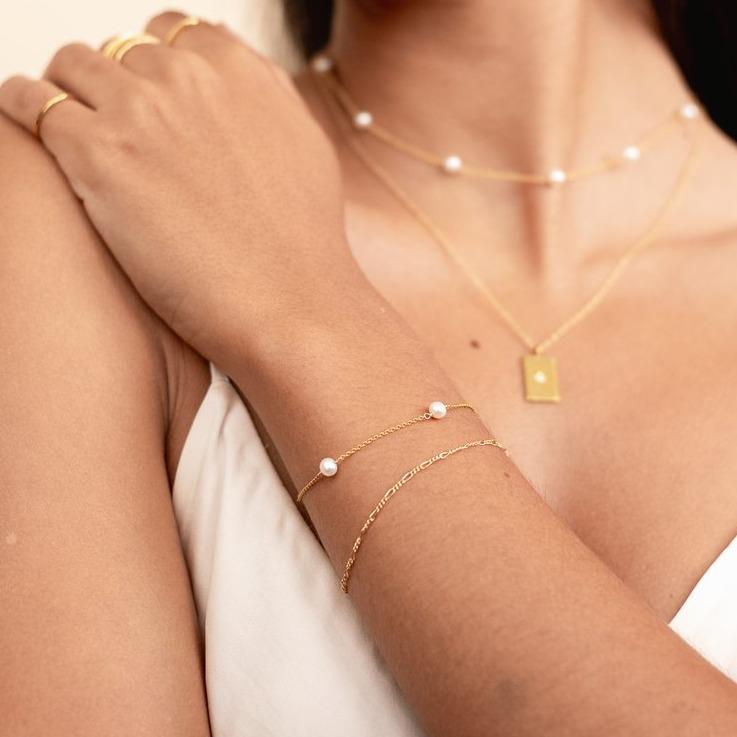 Pearl chain bracelet shown on a model crossing her arms and looking to the side, jewelry made by Katie Dean Jewelry