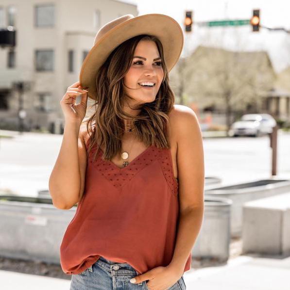 Effortless, boho chic in an urban setting, Kristin Rose Davis is smiling with a hat on and a maroon tank top wearing Katie Dean Jewelry necklaces