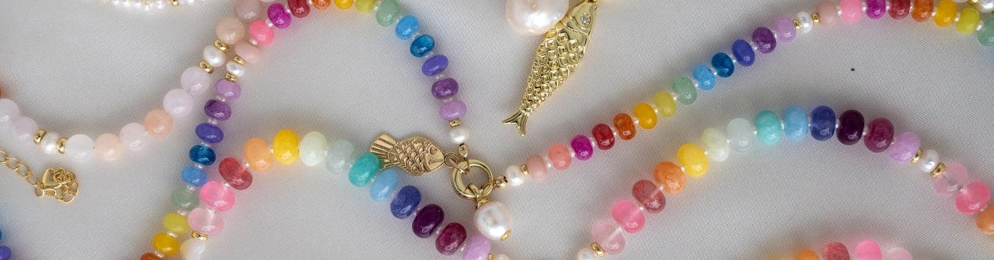 Colorful beaded necklaces in a rainbow hue on a white background