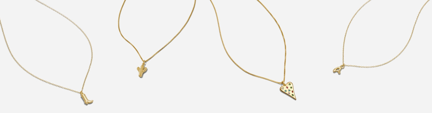 Katie Dean Jewelry dainty gold jewelry necklaces on a light grey background.