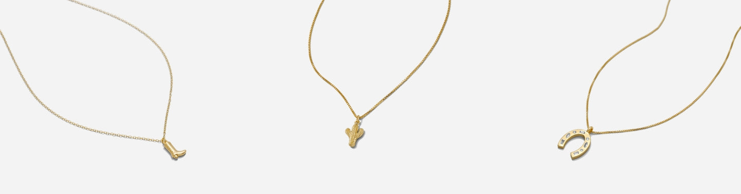 Western Collection by Katie Dean Jewelry featuring a dainty gold cactus necklace, cowgirl boot necklace and lucky horseshoe necklace, on a light grey background.