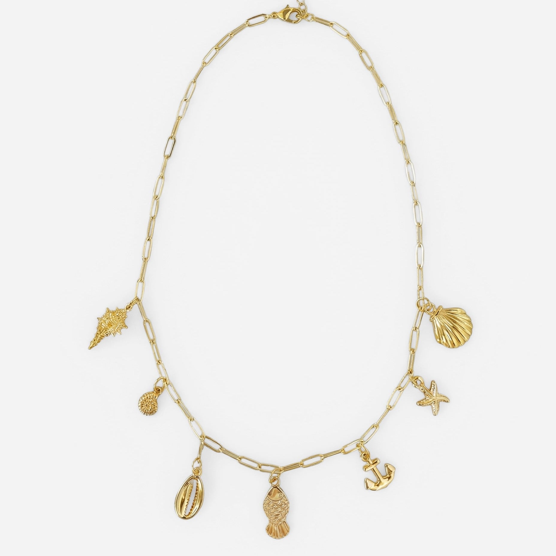 Coastal charm necklace with gold shell, starfish, anchor and fish charms on chain shown on a white background.