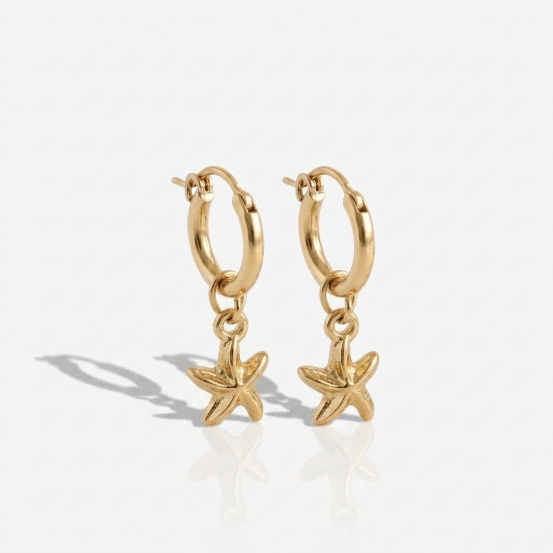 gold hoop earrings with starfish charm pendants on a white background