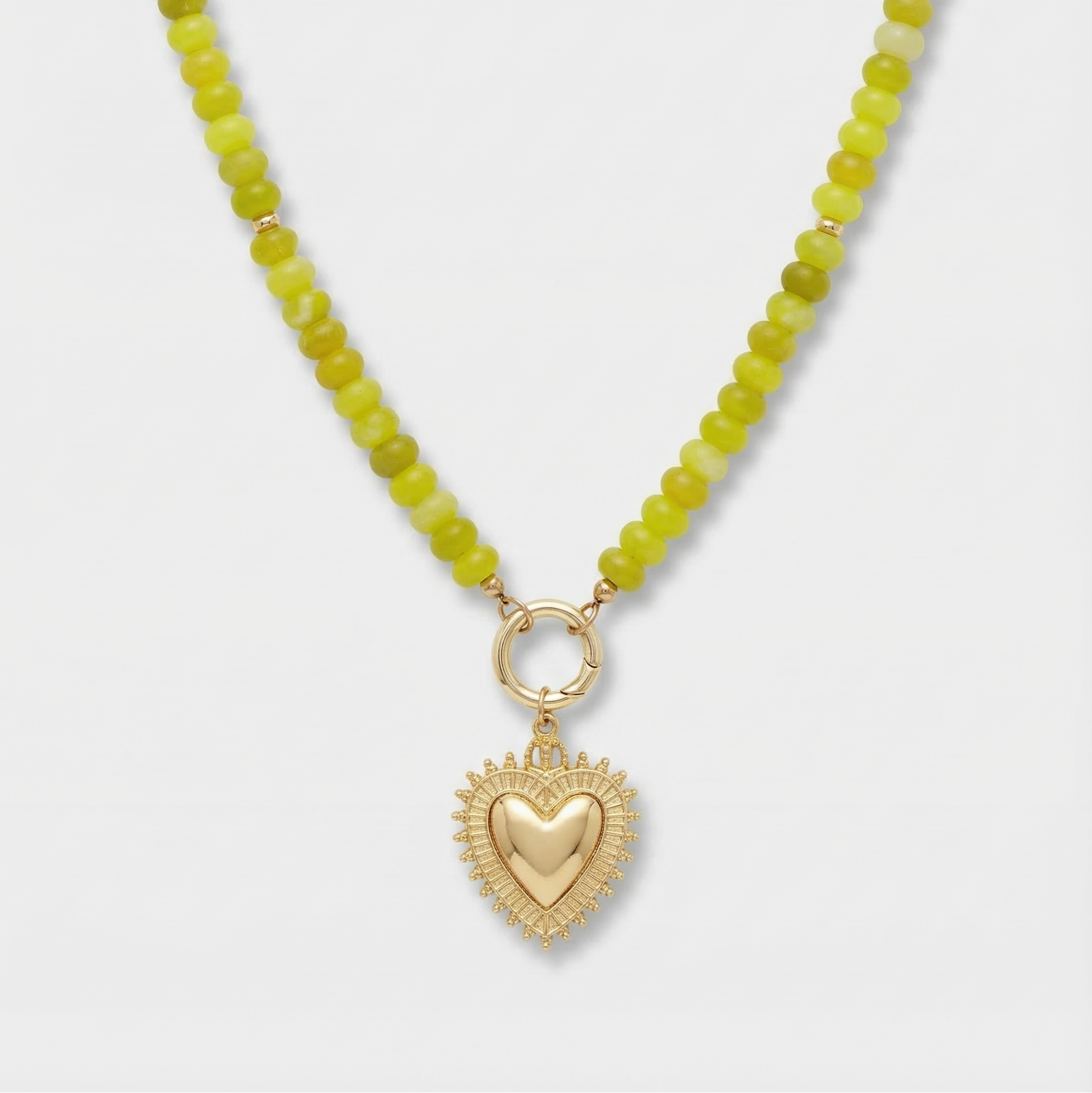 Necklace with green beads and a gold heart pendant on a white background