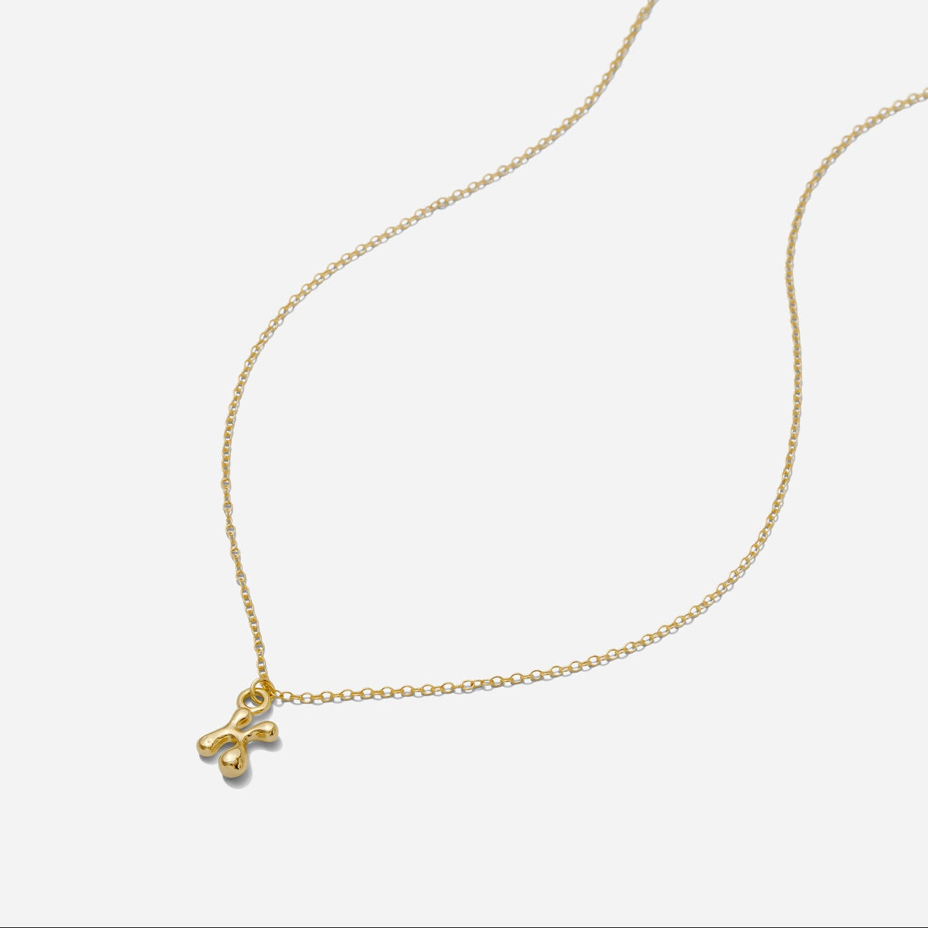 Dainty Gold puffy initial "K" pendant necklace on an 18-inch gold filled chain as seen on a white background.