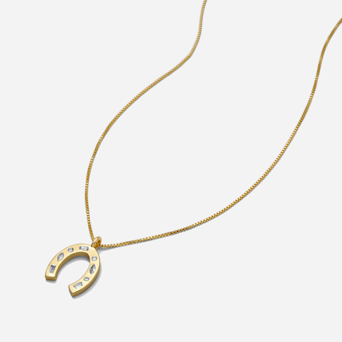 Dainty gold horseshoe pendant necklace with CZ stone accents on a delicate chain on a white background.
