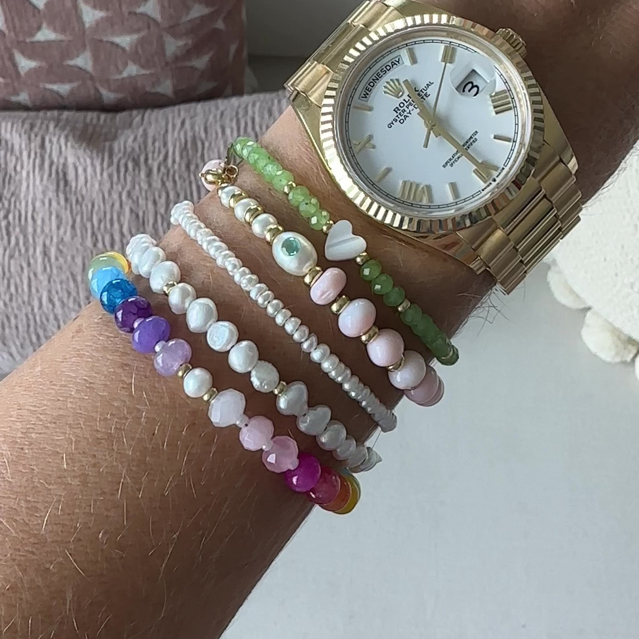 Multicolored beaded bracelet on a wrist alongside other beaded bracelets, handmade by Katie Dean Jewelry in Clearwater, Florida.