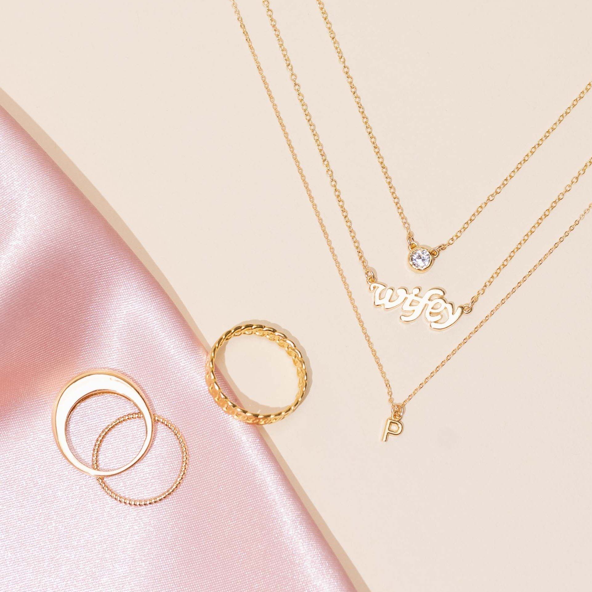 Dainty gold Wifey Necklace layered with a gold Birthstone Necklace and Initial Necklace, handmade in America by Katie Dean Jewelry