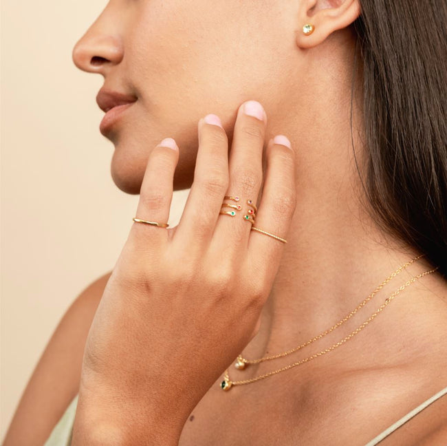 Model with hand on her chin showing three birthstone rings stacked on the middle finger.