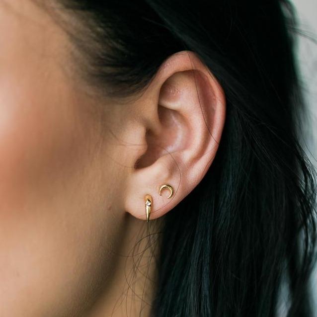 Gold crescent Moon Stud earrings on model with dark hair. Made by Katie Dean Jewelry.