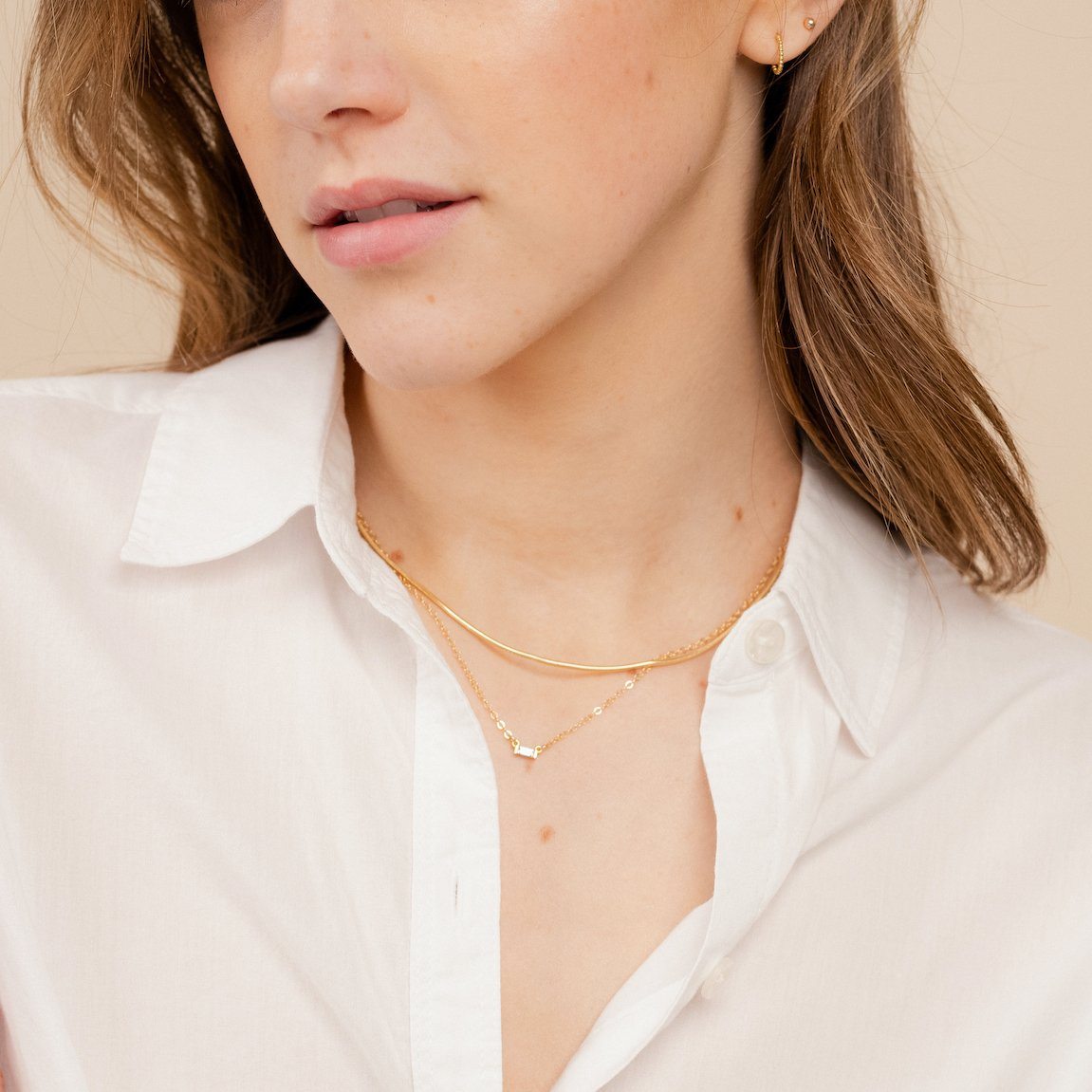 The dainty gold Elegant Necklace Set by Katie Dean Jewelry as seen on a model wearing a white button up collared shirt and dainty gold stud earrings