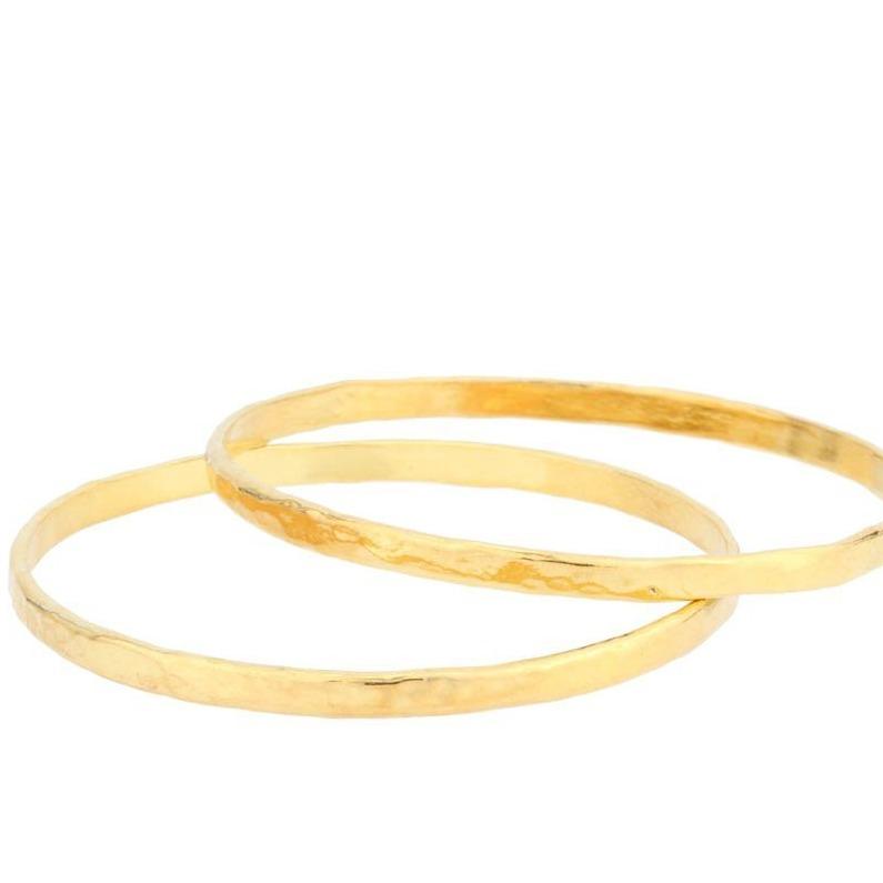 Up close image of two gold Hammered Bangles against a white background. 