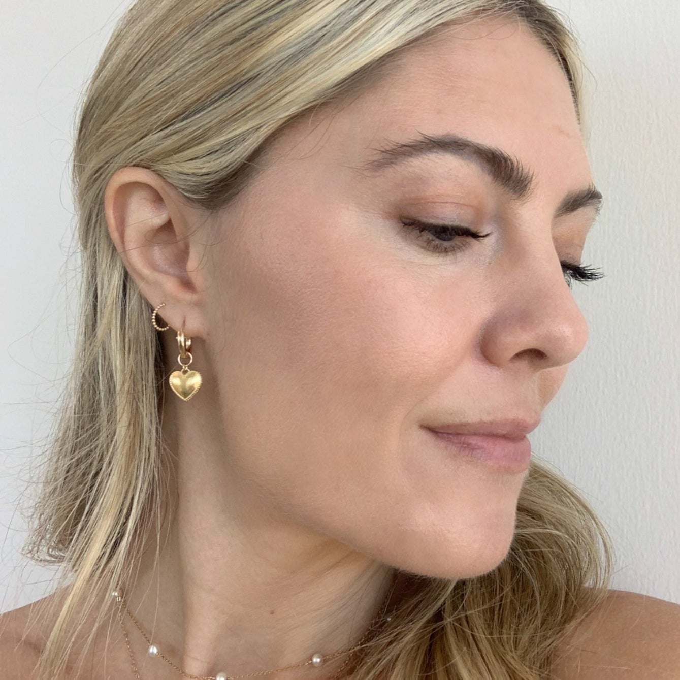 Dainty gold Heart Hoops hand crafted by Katie Dean Jewelry in America as seen on a model