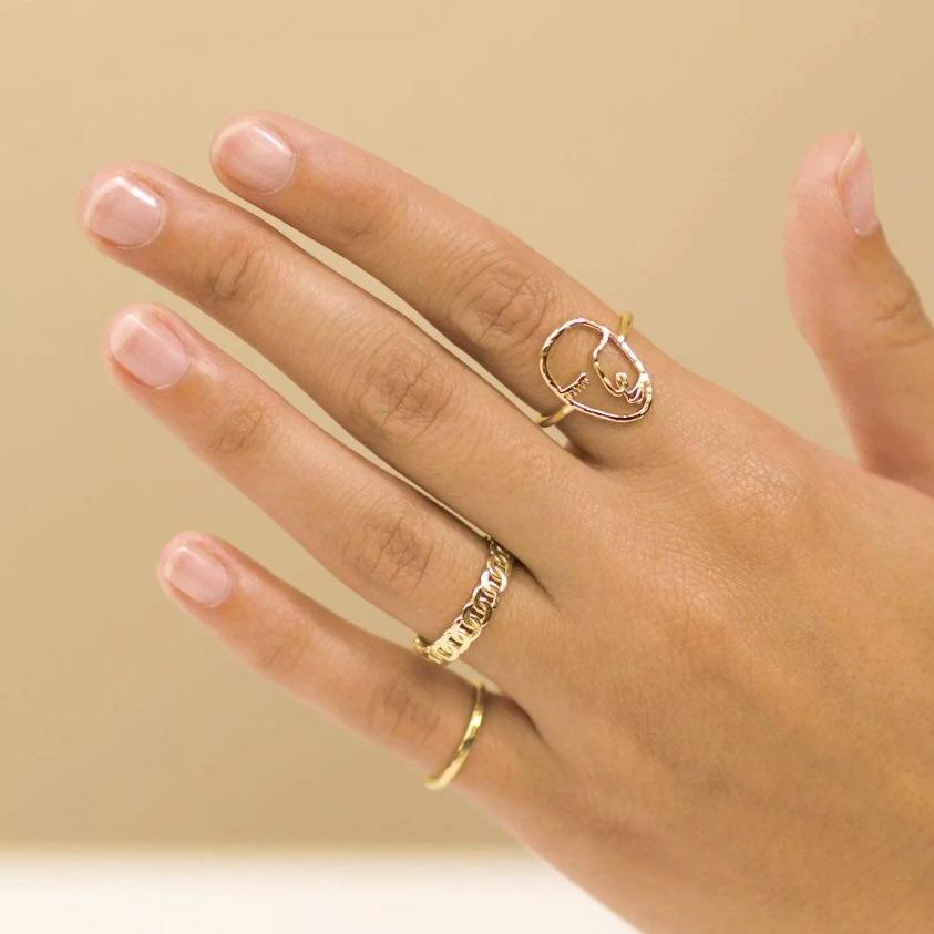 Dainty gold rings handmade by Katie Dean Jewelry, featuring the Artist Face Ring, Figaro Chain Ring and Hammered Band Stacking Ring. 