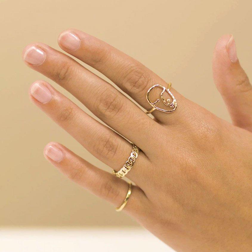 Dainty gold rings handmade by Katie Dean Jewelry, featuring the Artist Face Ring, Figaro Chain Ring and Hammered Band Stacking Ring. 